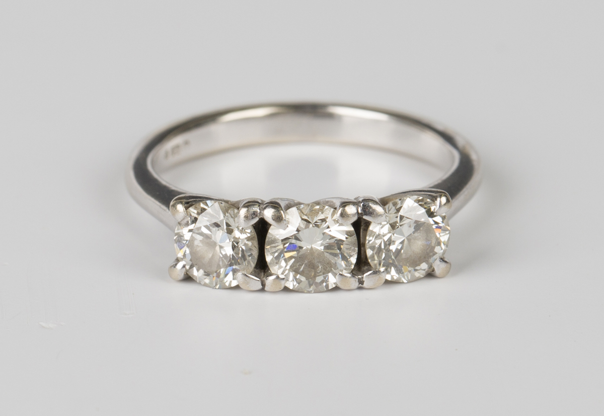 An 18ct white gold and diamond three stone ring, claw set with a row of circular cut diamonds,