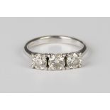 An 18ct white gold and diamond three stone ring, claw set with a row of circular cut diamonds,