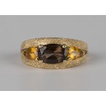 A 9ct gold ring, claw set with an oval cut smoky quartz between two pear shaped citrines,