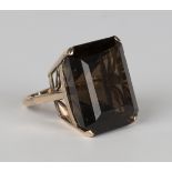 A gold ring, claw set with a large cut cornered rectangular step cut smoky quartz, the setting
