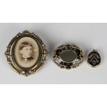 A Victorian gilt metal and black enamelled shaped oval mourning brooch, glazed with a central locket