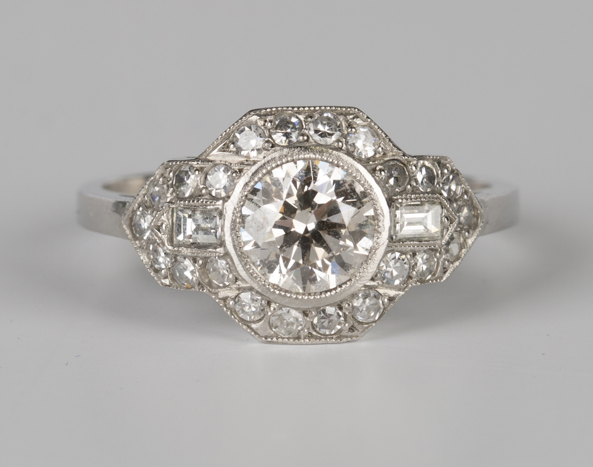 A platinum and diamond ring, collet set with the principal circular cut diamond in a geometric