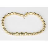 A gold necklace, designed as a row of graduated beads, on an associated spherical clasp with