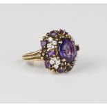 A gold, amethyst and diamond ring, claw set with the principal oval cut amethyst within a surround