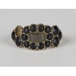 A George IV gold and faceted black paste mourning ring, glazed with a central locket compartment,