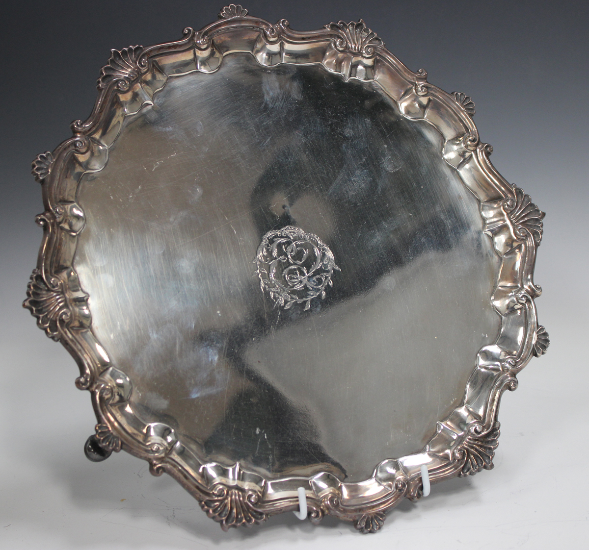 A George II silver salver with cast scalloped and scroll rim, framing a later engraved monogram to