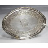 A George III Irish silver oval teapot stand with bright cut engraved foliate band and central crest,