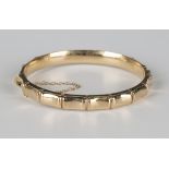 A 9ct gold oval hinged bangle of simulated bamboo design, on a snap clasp, fitted with a safety