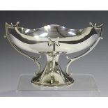 A George V silver comport with shallow shaped rim and three scroll supports, on a pedestal foot,