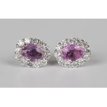 A pair of 18ct white gold, pink sapphire and diamond oval cluster earrings, each claw set with an