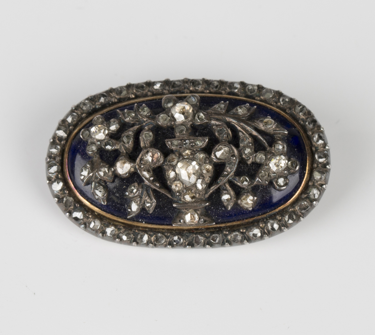 A mid-19th century diamond and dark blue enamelled, silver set and gold backed oval brooch, designed