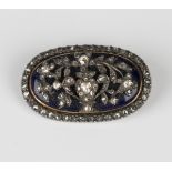 A mid-19th century diamond and dark blue enamelled, silver set and gold backed oval brooch, designed