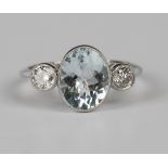 An aquamarine and diamond three stone ring, collet set with the oval cut aquamarine between two