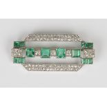 An emerald and diamond brooch in a geometric openwork design, mounted with twelve square cut