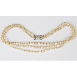 A three row necklace of graduated pearls, probably natural saltwater, on a diamond cluster clasp,