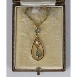 A gold, aquamarine and seed pearl pendant in an openwork drop shaped design, detailed '15ct', length