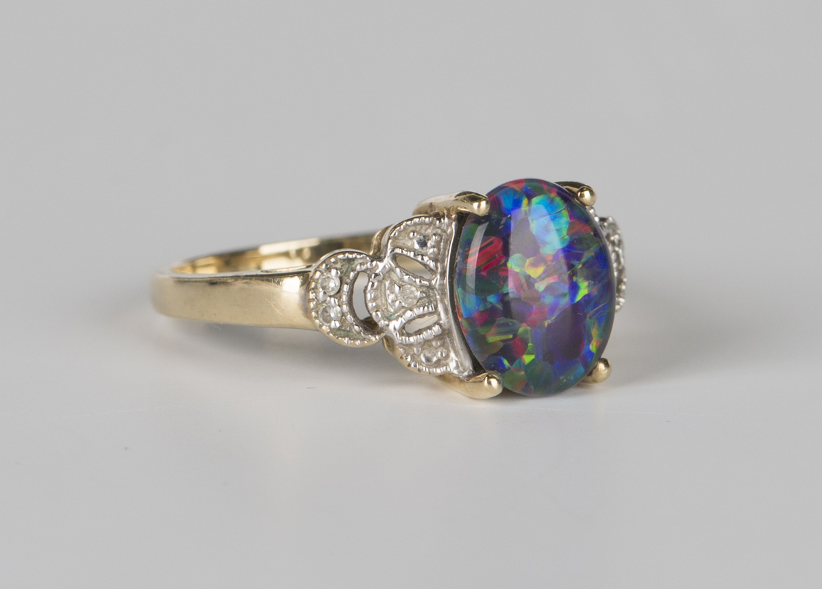 A 9ct gold ring, claw set with an oval opal triplet between diamond set pierced shoulders,