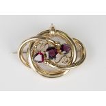 A Victorian gold and garnet brooch in an interlooped design, mounted with a cushion cut garnet