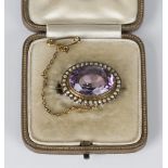 A gold, amethyst and seed pearl brooch, collet set with the oval cut amethyst within a surround of