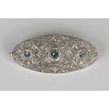 An aquamarine and diamond brooch in a pierced oval geometric design, mounted with three