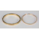 A 9ct gold oval hinged bangle with scroll engraved decoration, on a snap clasp, probably Chester