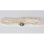 A three row necklace of graduated cultured pearls on a cultured pearl and colourless gem set oval