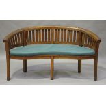 A modern teak banana garden bench of curved form, fitted with a cushion, height 84cm, width 159cm,