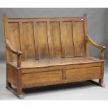 A 19th century provincial pine panelled back settle, the box seat and scroll arms raised on sledge