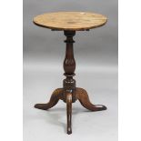 An 18th century provincial oak circular wine table, on a turned baluster column and tripod