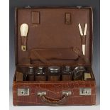 An early 20th century crocodile skin travelling vanity case, the interior fitted with six silver-