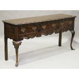 A 20th century George II provincial style oak dresser base with yew crossbanding and carved cabriole