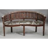 A 20th century hardwood banana garden bench of curved form, height 84cm, width 157cm, depth 65cm (