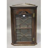 A small George III mahogany hanging corner cabinet, the astragal glazed door with a carved fan