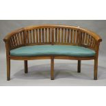 A modern teak banana garden bench of curved form, fitted with a cushion, height 84cm, width 159cm,