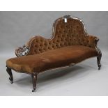 A Victorian walnut carved showframe chaise-longue, upholstered in buttoned chocolate brown velour,