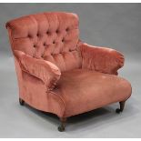 A late Victorian buttoned back scroll armchair, probably by Howard & Sons, raised on turned and