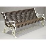 A 20th century white painted cast iron and wooden slatted garden bench, in the manner of
