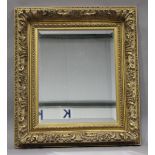 A modern gilt composition wall mirror, the bevelled plate within a foliate scroll frame, 89cm x