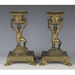 A pair of Regency gilt bronze figural table stands, each campana urn surmount supported by a