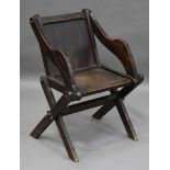 An early 20th century oak Glastonbury chair, the solid seat and back raised on 'X' frame supports,