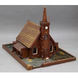 An early 20th century primitive model of a church, the hinged lid revealing an interior with pews,