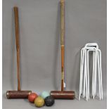 Two early 20th century croquet mallets, four balls and a set of hoops.Buyer’s Premium 29.4% (