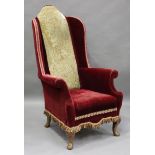 An early 20th century Queen Anne style wingback armchair, the needlework back and claret velour seat