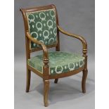 An early 19th century French Empire period walnut framed armchair, the scrolling back and bowfront