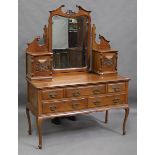 An Edwardian walnut dressing table, the swing mirror flanked by carved jewellery cabinet doors,