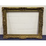 A large gilt composition picture frame with shell and foliate scroll crestings, rebate 106cm x 82cm,