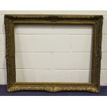 A carved and gilt composition picture frame with foliate scroll decoration, rebate 71.5cm x 92.