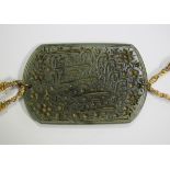 An Islamic green jade arm ornament of oblong form with curved ends, incised with script, length