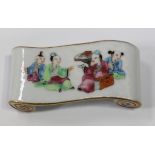 A Chinese famille rose porcelain brush rest, late Qing dynasty, of scroll form, the top painted with