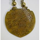An Islamic yellow agate pendant of shield shape, finely incised and gilt with lines of script, width